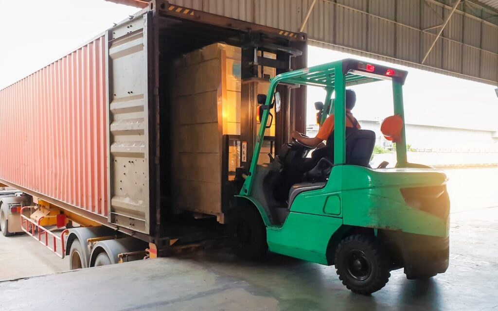 Forklift at warehouse loading boxes onto shipping container