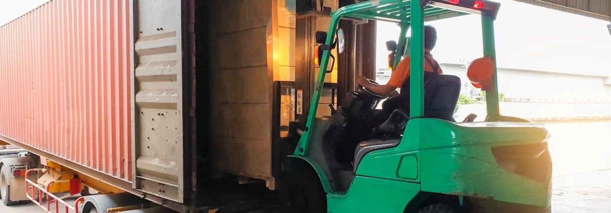 Forklift at warehouse loading boxes onto shipping container
