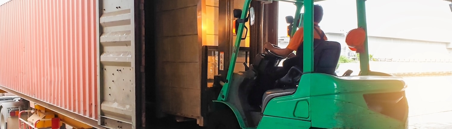 Forklift at warehouse loading boxes onto shipping container