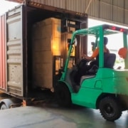 Forklift at warehouse loading boxes onto shipping container