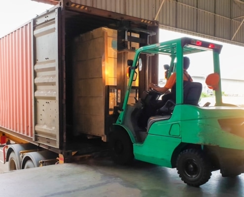 Forklift at warehouse loading boxes onto shipping container